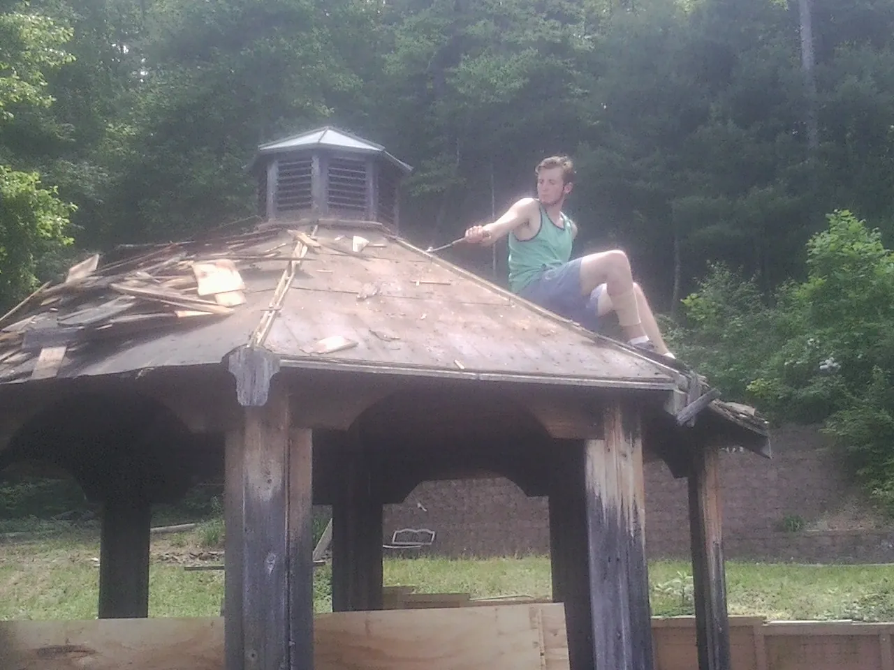 Tearing the old roof off a wooden gazebo before new shakes in Tyler
