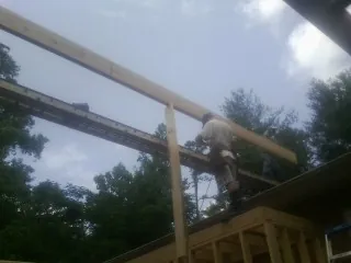 Carpenter setting a ridge beam over a new addition frame — Ice Dam Removal by Roofing Brothers in Tyler