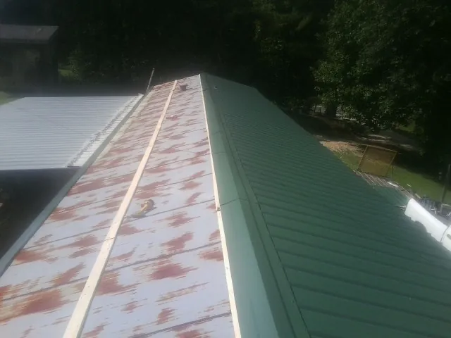 Old rusted panels beside newly installed green metal roofing — Wind Damage Roof Repair by Roofing Brothers in Tyler