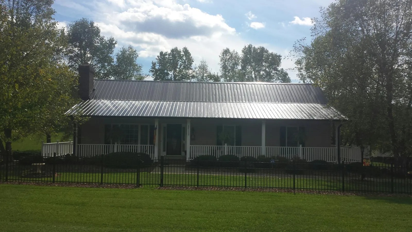 Gray metal roof on a brick ranch with a full width front porch — Gutter Guard Installation work by our crew in Tyler